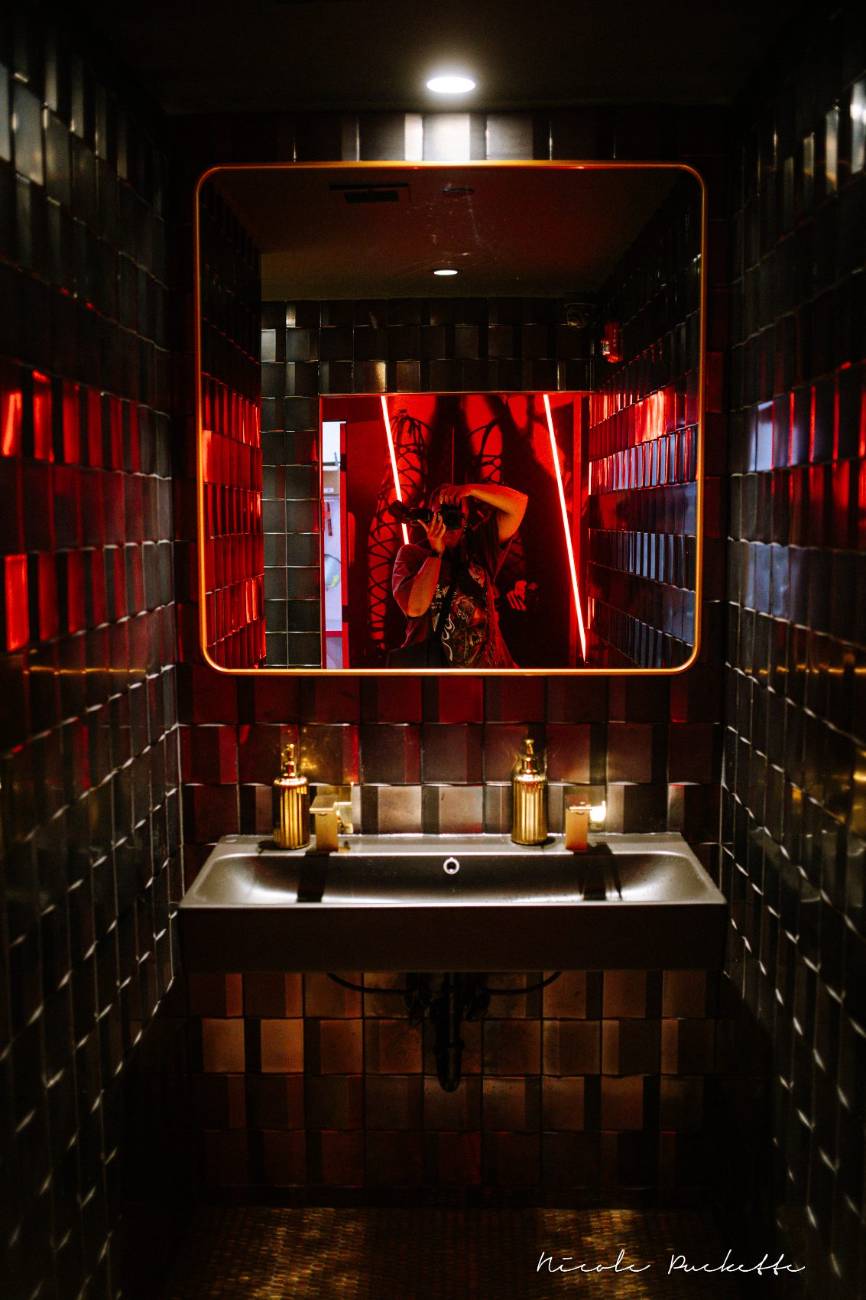 Tiled powder room with a gold-framed mirror off the Red Room
